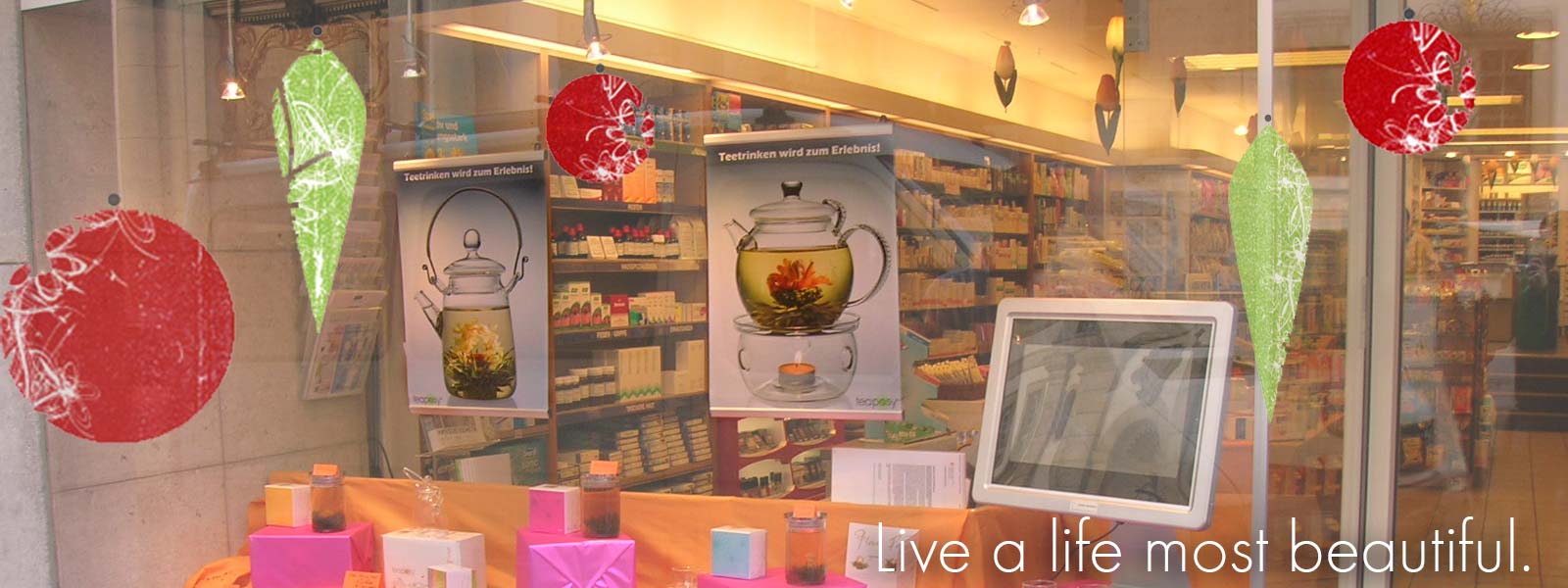 A holiday gift shop window with Teaposy blooming tea posters hanging along with other decorations