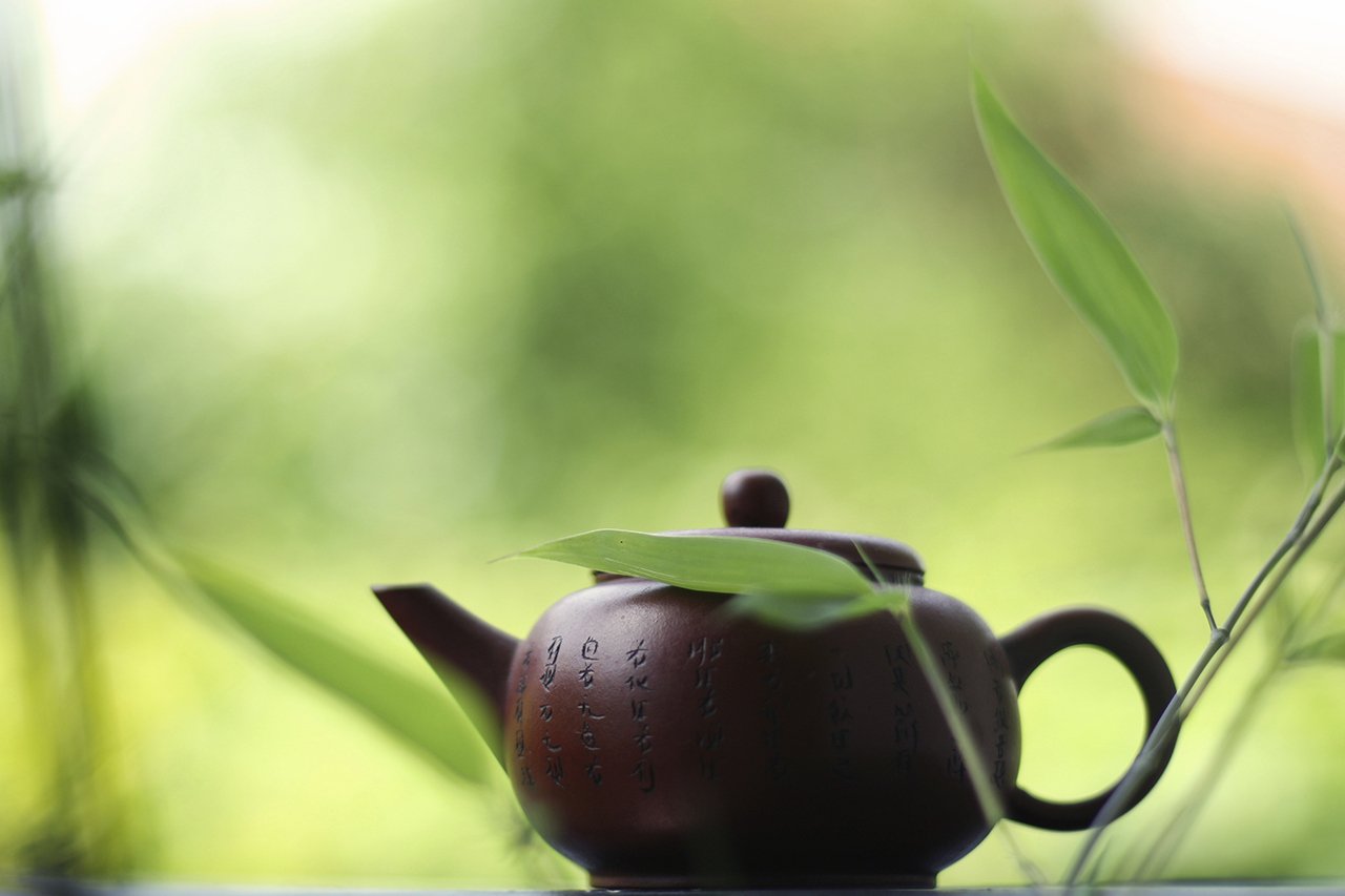 A stone teapot surrounded by green bamboo leaves